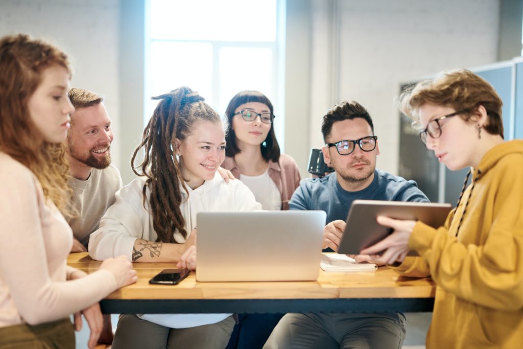 a group of people sitting at a table looking at a laptop