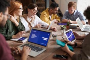 a group of people sitting at a table with laptops