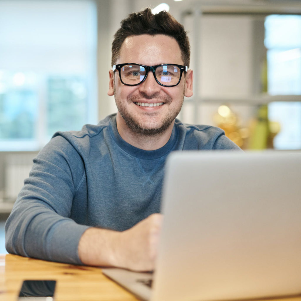 a man wearing glasses and smiling at the camera