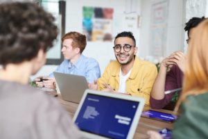 a group of people sitting around a table with laptops