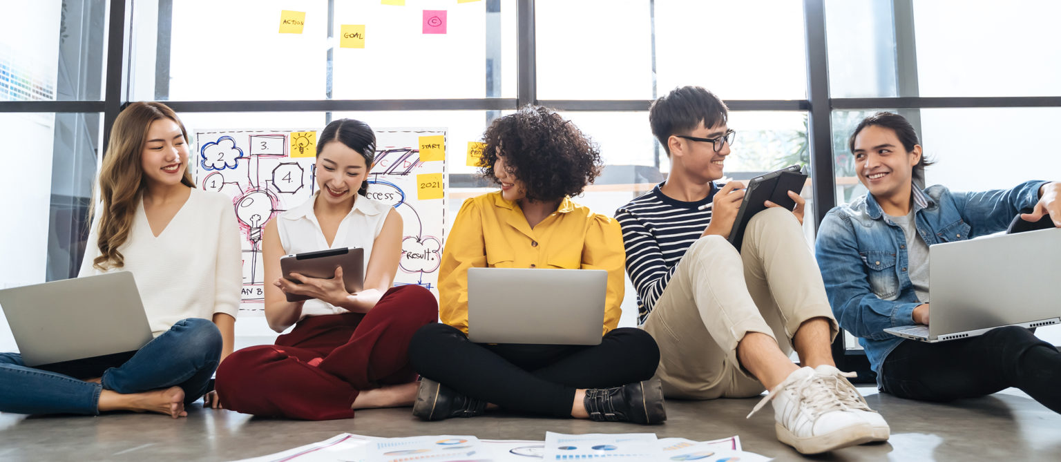 a group of people sitting on a couch looking at laptops