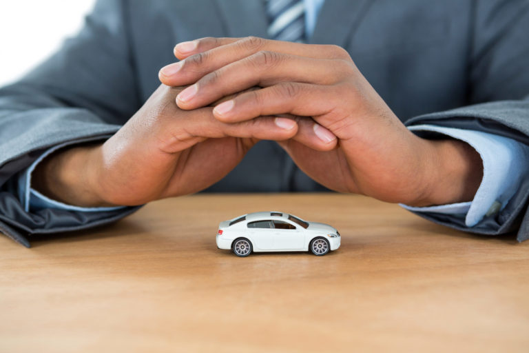 Businessman protecting toy car with hands