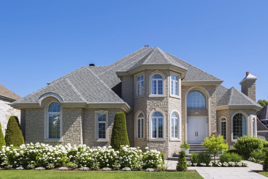 Facade of luxurious house in beige stone with front garden